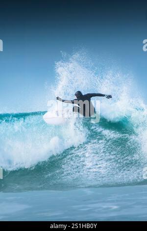 Un surfeur qui fait une vague à Fistral à Newquay, en Cornouailles, au Royaume-Uni. Banque D'Images