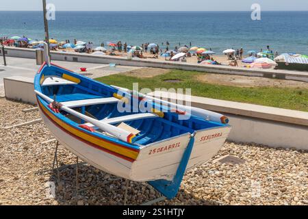 Sesimbra, Portugal. 8 août 2024. Bateau de pêche traditionnel et coloré sur la côte de l'océan Atlantique avec une plage pleine de gens. Sesimbra Portu Banque D'Images