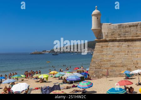 Sesimbra, Portugal. 8 août 2024. Tour de guet d'un fort surplombant l'océan Atlantique, les gens sur la plage. Sesimbra Portugal. Banque D'Images