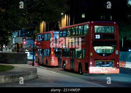 London Night bus Scene, Une photographie nocturne animée capturant les autobus à impériale rouges emblématiques dans les rues de Londres. Banque D'Images