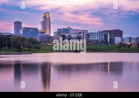 Vue de l'horizon d'Omaha Nebraska au coucher du soleil vu depuis Heartland of America Riverside Park avec le lac en vue. Banque D'Images