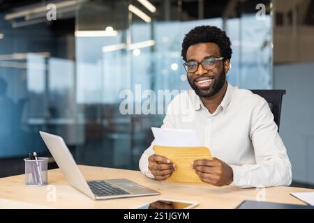 Portrait d'un homme d'affaires heureux prospère, homme regardant la caméra tenant une enveloppe postale, employé a reçu une notification renard sur les bons résultats obtenus sur le lieu de travail. Banque D'Images