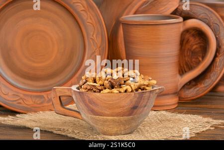 Noix décortiquées dans un bol en bois, macro, sur fond de plats en argile. Banque D'Images