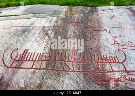 Recopie des sculptures rupestres de Tanum sur la roche plate de Vitlycke, peinte en rouge, représentant des bateaux, des gens et des animaux, datant des âges du bronze et du fer. Banque D'Images