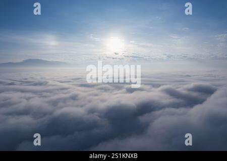 Vue aérienne de la lumière du soleil radieuse sur le brouillard et le nuage moelleux le matin, créant une atmosphère tranquille Banque D'Images