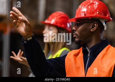 Deux ouvriers de la construction portant des gilets de sécurité et des casques communiquent efficacement sur un chantier. L'image met en évidence le travail d'équipe, la sécurité et l'efficacité Banque D'Images