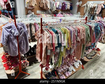 Kiev, Ukraine - 04 janvier 2025 : une vitrine vibrante de vêtements et de chaussures pour enfants soigneusement disposés dans un magasin contemporain. Banque D'Images