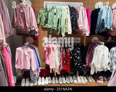 Kiev, Ukraine - 04 janvier 2025 : une variété de vêtements et de chaussures colorés pour enfants exposés soigneusement dans un cadre de magasin de détail. Banque D'Images