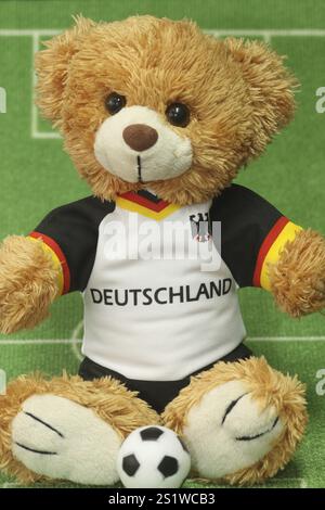 Ours en peluche dans un maillot de football sur un fond vert Banque D'Images