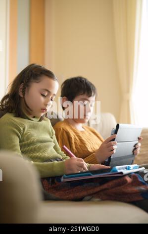 Deux enfants étudient à la maison avec une tablette Banque D'Images