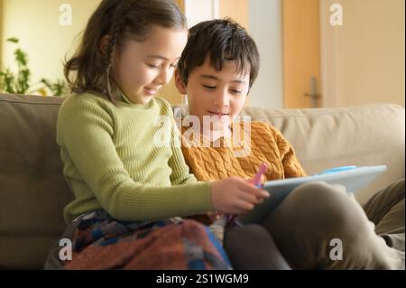 Deux enfants étudient à la maison avec une tablette Banque D'Images