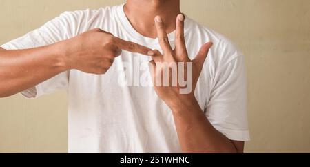 Jeune homme levant les mains tout en parlant sur la langue des signes, montrant le comptage des mots Banque D'Images