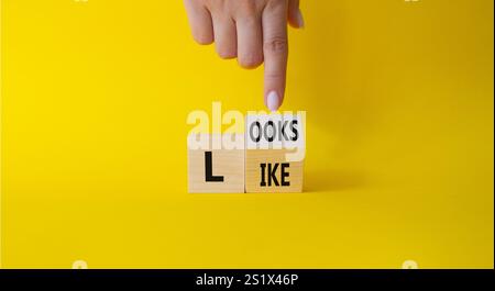 Ressemble à un symbole. La main d'homme d'affaires pointe à des cubes en bois tournés avec des mots ressemble. Beau fond jaune. Business et ressemble à concept. Banque D'Images