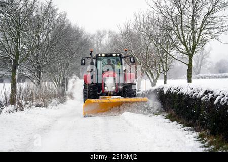 Un tracteur dégage la neige d'une route à Scotton, Harrogate, North Yorkshire. Les fortes chutes de neige nocturnes provoquent des perturbations dans tout le Royaume-Uni alors que le début froid de la nouvelle année se poursuit. Date de la photo : dimanche 5 janvier 2025. Banque D'Images