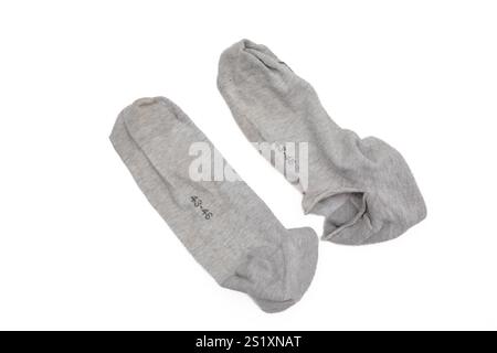 Paire de chaussettes grises avec un grand trou en un, gros plan de tissu déchiré, sur fond blanc Banque D'Images