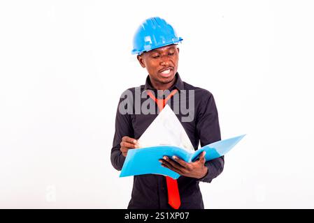 portrait d'un jeune ingénieur portant un casque de sécurité lit et vérifie des documents. Banque D'Images