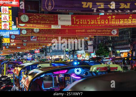 Scène nocturne animée et animée pendant les célébrations du nouvel an chinois dans le quartier chinois de Bangkok, avec tuk-tuks, enseignes au néon et bannières rouges festives Banque D'Images