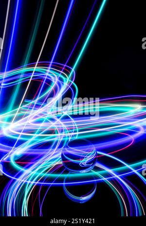 Tourbillons de lumière colorée dans une photographie à longue exposition autour d'une boule de verre sur un miroir. Reflets et tourbillons de fond clair Banque D'Images