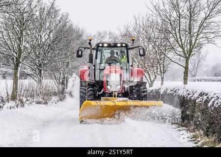 Un tracteur dégage la neige d'une route à Scotton, Harrogate, North Yorkshire. Les fortes chutes de neige nocturnes provoquent des perturbations dans tout le Royaume-Uni alors que le début froid de la nouvelle année se poursuit. Date de la photo : dimanche 5 janvier 2025. Banque D'Images