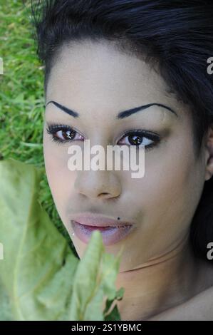 Jeune adulte jeune vêtu de race mixte femme noire couchée sur l'herbe rêvant dehors Banque D'Images