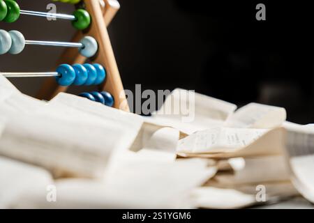 Une pile de papiers et un boulier en bois sont sur une table. Le boulier est placé au-dessus des papiers, et c'est une calculatrice simple et basique Banque D'Images