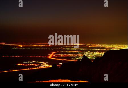 Une vue de nuit sereine depuis Jebel Hafeet, avec les lumières de la ville et un ciel étoilé. Banque D'Images