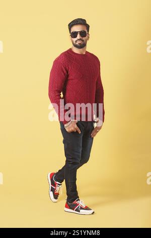 Un modèle masculin asiatique posant en pull rouge sur fond jaune dans le style Banque D'Images