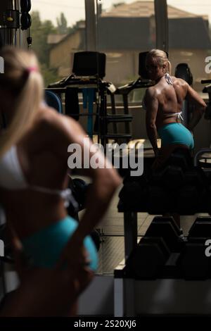 Femme athlétique capturée dans des poses étonnantes tout en réfléchissant dans Un miroir de gymnastique - mettant en évidence sa physique tonique et sa force Banque D'Images