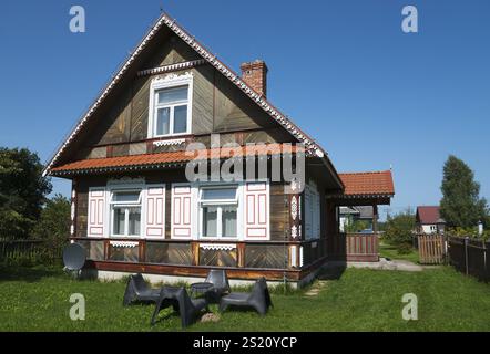 Maison traditionnelle brune en bois avec chaises noires dans le jardin ensoleillé, Budy, BiaNowieZa, Bialowieza, Podlaskie Voivodeship, Podlaskie, Pologne, Europe Banque D'Images