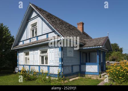 Maison traditionnelle en bois bleu et blanc avec des fleurs au premier plan par une journée ensoleillée, Budy, BiaNowieZa, Bialowieza, Podlaskie Voivodeship, Podlaski Banque D'Images