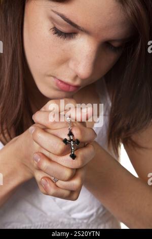 Les mains de la jeune fille pliées dans la prière avec une croix les mains de la jeune fille pliées dans la prière avec une croix Banque D'Images