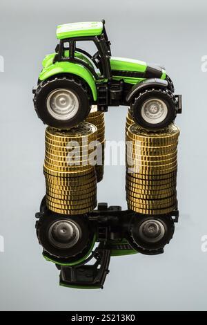 Les agriculteurs du secteur agricole doivent tenir compte de l'augmentation des coûts. Des prix plus élevés pour les aliments pour animaux, les engrais et les plantes. Tracteur avec pièces de monnaie Banque D'Images