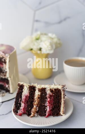 Gros plan d'une tranche de gâteau au chocolat avec garniture aux baies et glaçage à la crème servi sur l'assiette. Banque D'Images