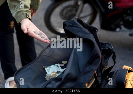 Fille de beauté donnant de l'argent aux hommes sans-abri. Homme de couple sans-abri jouant de la guitare demandant un don d'argent Banque D'Images