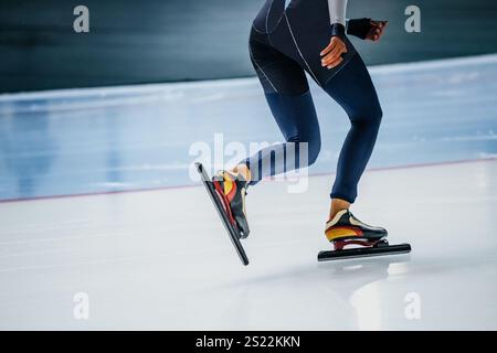 patineuse de vitesse féminine jambes en costume de peau bleu foncé et patins Banque D'Images