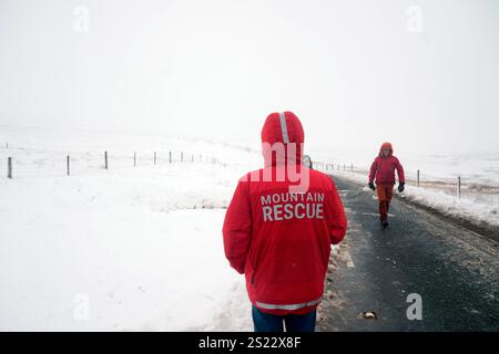 Les membres d'une équipe Mountain Rescue après avoir aidé à dégager des voitures d'une dérive de neige près de Ribblehead, dans le North Yorkshire. De grandes parties du Royaume-Uni sont confrontées à de fortes chutes de neige et à des pluies verglaçantes, ce qui est susceptible de causer des perturbations, après l'entrée en vigueur de deux avertissements météorologiques jaunes. Des véhicules bloqués sur les routes, des voyages ferroviaires et aériens retardés ou annulés, et des coupures de courant sont tous probables alors que le pays est aux prises avec une période hivernale d'une semaine, a déclaré le met Office. Date de la photo : lundi 6 janvier 2025. Banque D'Images