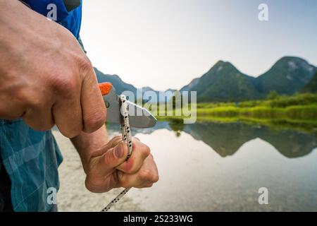 Vue détaillée de l'homme coupant la corde avec un couteau. Banque D'Images