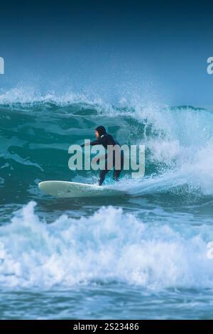 Un surfeur qui fait une vague à Fistral à Newquay, en Cornouailles, au Royaume-Uni. Banque D'Images