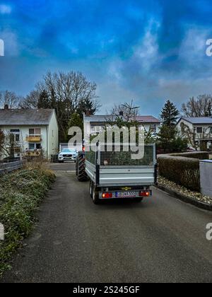 Un tracteur avec une remorque dans une rue de la ville, qui rassemble des arbres de Noël après les vacances. Collecte des arbres de Noël usagés pour les dispos appropriés Banque D'Images