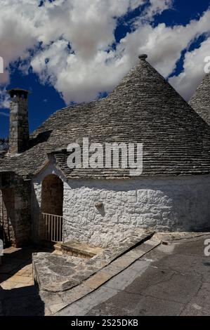 Les dalles de calcaire courtisées, serrées et entrelacées pour la force, atteignent un ciel spectaculaire au-dessus des trulli mondialement célèbres d'Alberobello, dans les Pouilles, en Italie. Les trulli, maisons traditionnelles en pierre sèche ou murs secs surmontées de cônes ou de dômes, sont maintenant pour la plupart restaurés et réutilisés comme maisons, maisons de vacances, magasins et musées. Banque D'Images