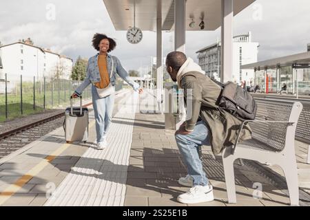 Heureux jeune couple afro-américain serrant dans ses bras à une gare, se réunissant après un long voyage. Concepts de voyage, d'accueil et d'amour. Banque D'Images