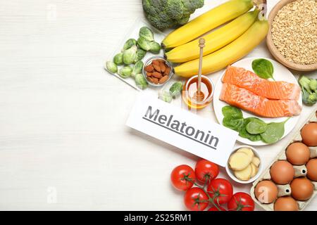 Mot mélatonine et différents produits sur table en bois blanc, pose à plat. Espace pour le texte Banque D'Images