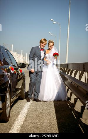 Beau couple nouvellement marié marchant sur l'autoroute à la journée ensoleillée Banque D'Images