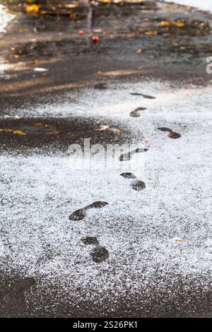 Dans l'empreinte dans la ville humide park première couverte par la neige en automne Banque D'Images