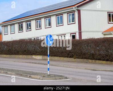 Un panneau de signalisation tournant à gauche se trouve dans une rue calme dans un quartier résidentiel. Les panneaux solaires sont visibles sur les toits des maisons voisines, mettant en valeur Banque D'Images