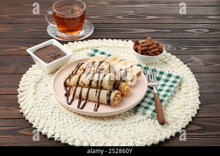 Délicieuses crêpes avec sauce chocolat et banane servies sur une table en bois Banque D'Images