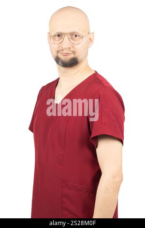 Un travailleur de la santé homme chauve avec une barbe porte des gommages médicaux rouges et des lunettes. Banque D'Images