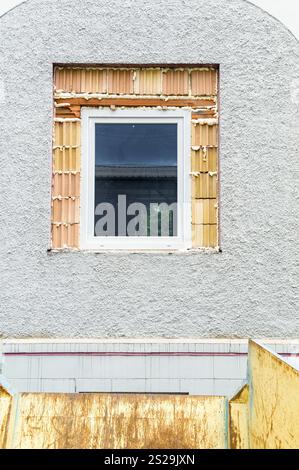 De nouvelles fenêtres sont installées dans une ancienne maison pour économiser les coûts de chauffage. Rénovation et rénovation de maisons anciennes Banque D'Images