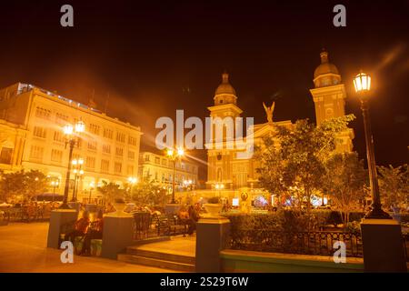 La cathédrale basilique de notre-Dame de l'Assomption façade avec ses tours jumelles et statue d'ange dans le Parque Cespedes la nuit, au centre-ville de Santiago de Cu Banque D'Images