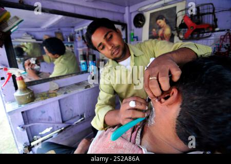 Un homme se rasant dans un petit salon de coiffure à Ayodhya, en Inde. Banque D'Images